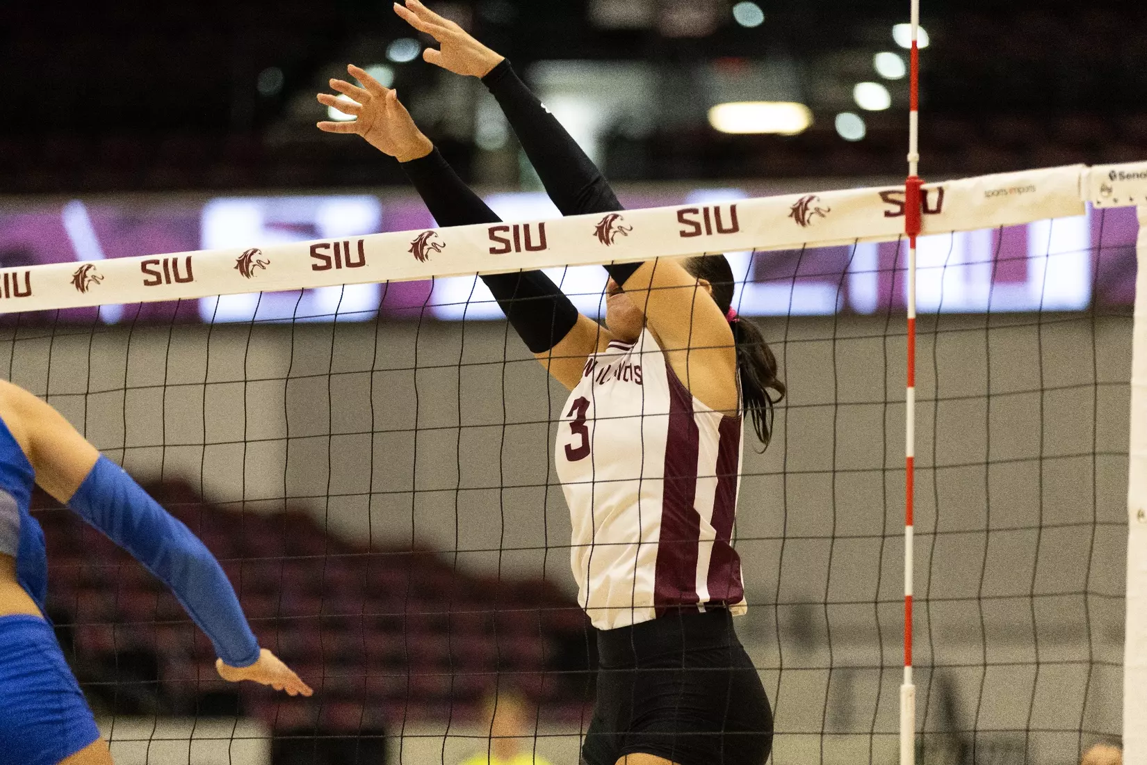 McKenzie Moeller jumps over the net and blocks a ball.