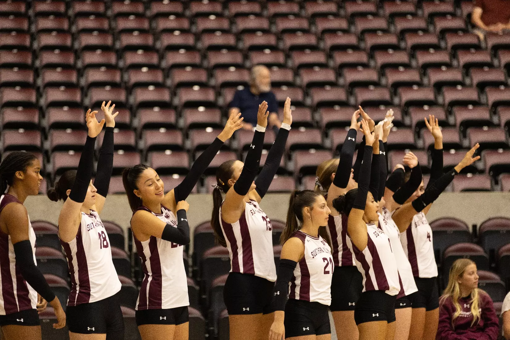 The bench throws their hands up in an attempt to distract the incoming serve.