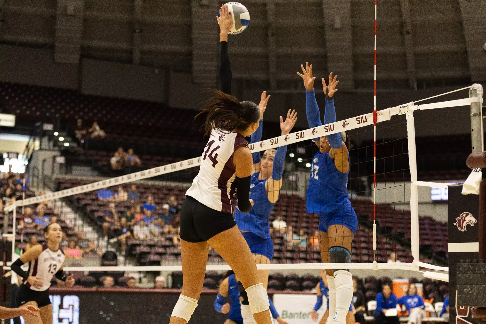 Ella Swansiger spikes a ball over the net and blocker's arms.