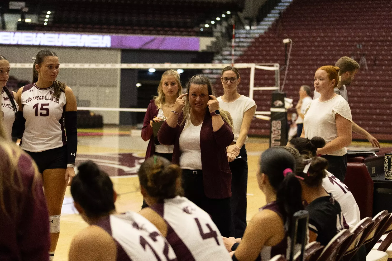 Head Coach Brittany Harry points to her head and talks to her team during a timeout.