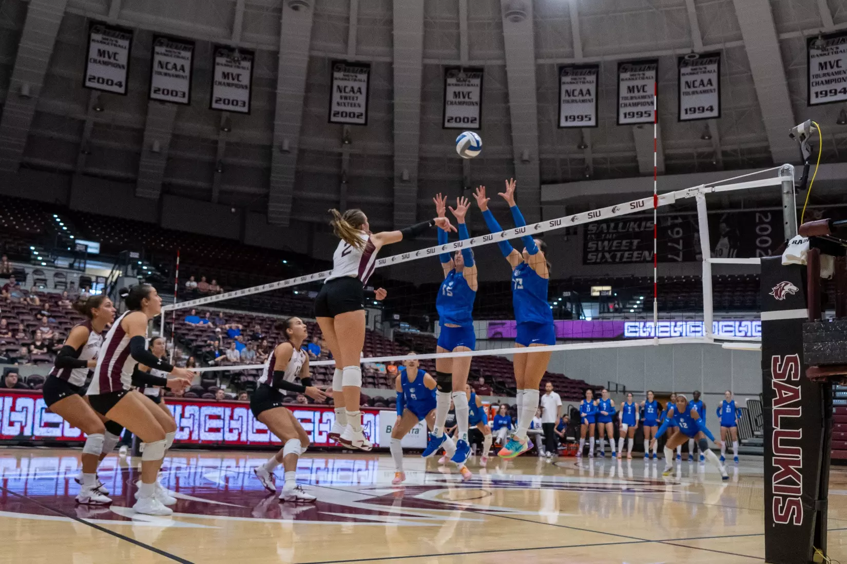 Natalie Vance spikes a ball over the arms of blockers.
