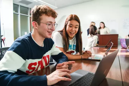 Two students working on a laptop