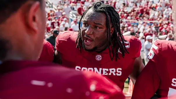 OU defensive lineman David Stone speaks to his teammates, in crimson uniforms, in a huddle prior to a game during the 2026 season.