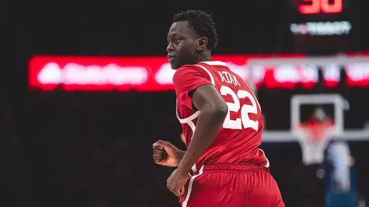 Kuol Atak in red Oklahoma basketball uniform looking back as he runs down the court
