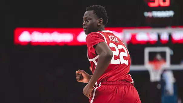 Kuol Atak in red Oklahoma basketball uniform looking back as he runs down the court