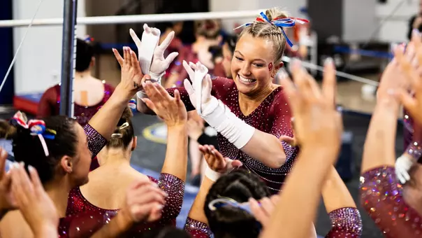 Ella Murphy high-fives her teammates after her bar routine against Kentucky.