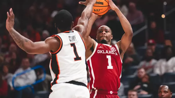 Xzayvier Brown in red uniform shoots a jump shot over a defender in white uniform