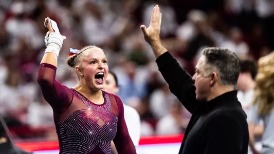Hannah Scheible high-fives associate head coach Lou Ball after her bars routine