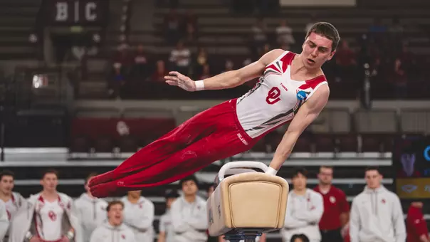 Ignacio Yockers in red pants and white tank top, performs a pommel horse routine at McCasland Field House