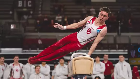 Ignacio Yockers in red pants and white tank top, performs a pommel horse routine at McCasland Field House