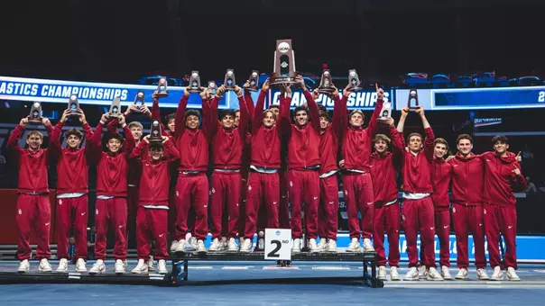 The Oklahoma men's gymnastics team hoists its NCAA runner-up trophy on the podium following the 2026 NCAA Men's Gymnastics Championships at State Farm Center in Champaign, Ill.