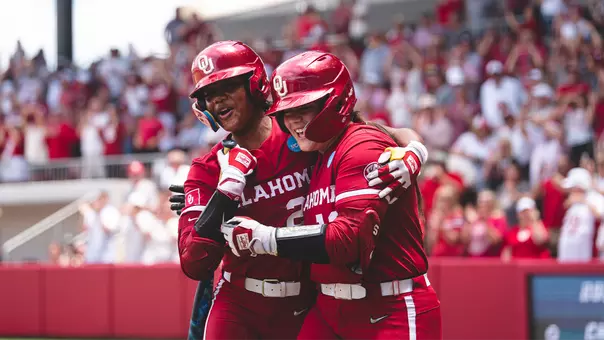 Lexi McDaniel and Kai Minor hug after a McDaniel three-run pinch hit home run