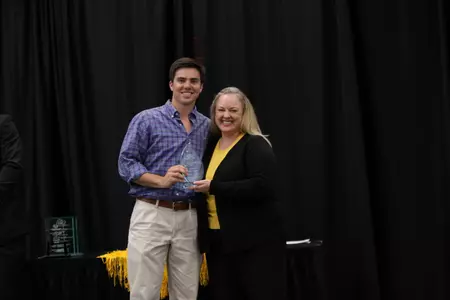 Corey Acosta accepts Outstanding Scholar Award from Director of Academics Stacy Breazeale.
