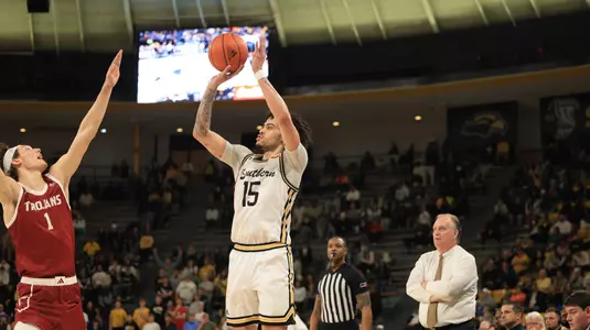 Southern Miss Golden Eagles guard Donovan Ivory (15) with a three point shot over Troy Trojans forward Thomas Dowd (1) as Southern Miss Golden Eagles head coach Jay Ladner looks on in a game between the Southern Miss Golden Eagles and the Troy Trojans in a NCAA Men's Basketball game. January 20, 2024. (Joe Harper/bgnphoto.com)