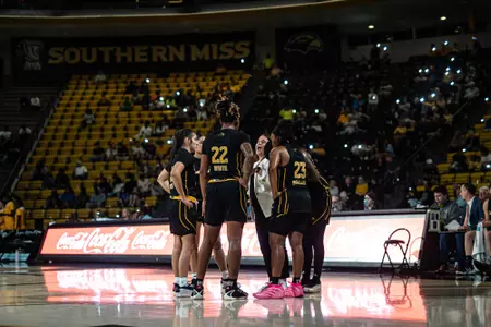 Lady Eagles huddle on the floor with Missy Bilderback during light show