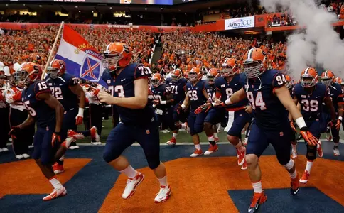 The SU team runs onto the field at the start of the game.
