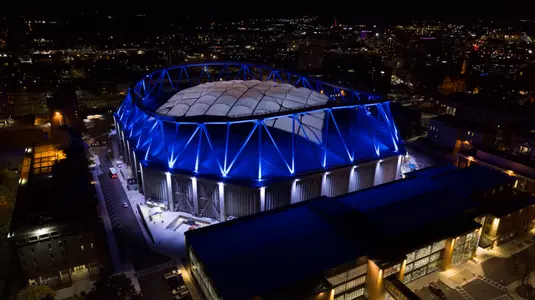 An aerial shot of the Syracuse University Stadium lit up at night.