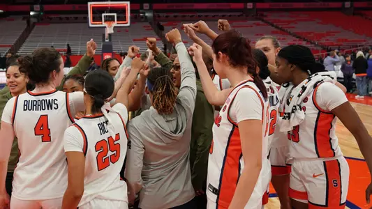 Women's Basketball team huddles after a win.
