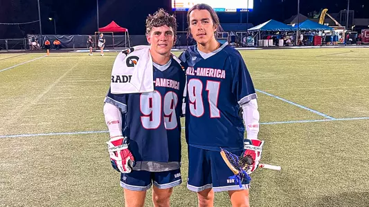 Jake Spallina and Trey Deere stand next to each other at IL All-America. Both wear dark blue jerseys with #99 and #91, respectively.