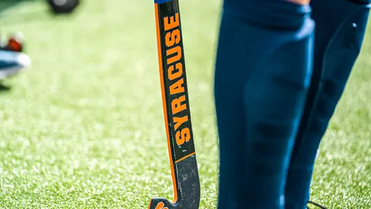 A field hockey stick branded with an orange SYRACUSE on a black surface.