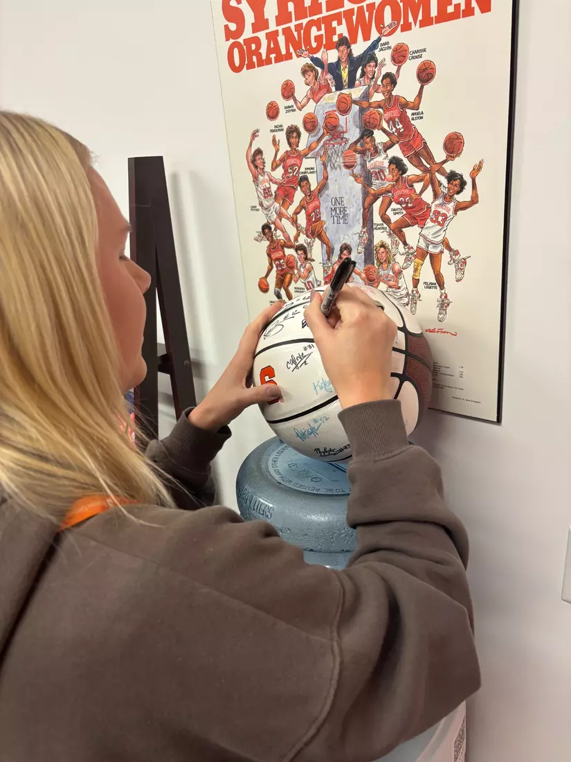 Brooke Alexander signing the Alumni WBB ball