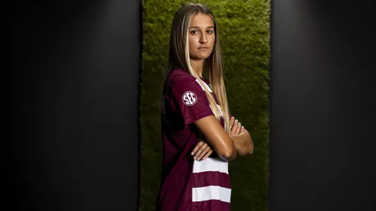 Katie Smith stares menacingly at the camera in a portrait shoot featuring a black and turf backdrop. Hashtag lit and fire.