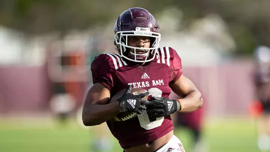 Ainias Smith runs with a ball at practice, April 5, 2021