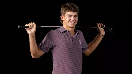 Aaron Pounds in front of stark black background at his portrait shoot.