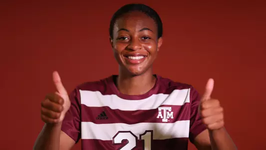 Jazmine Wilkinson gives double gigems in front of a fancy maroon backdrop at her portrait shoot.