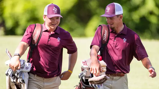 William Paysse and Sam Bennett share a precious moment on the course as they lug their bag full of golf clubs at the Aggie Invitational