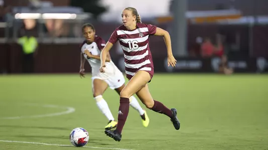 Carolyn Calzada is in a full sprint with the ball at the center circle on transition.