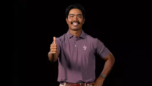 Phichaksn Maichon gives a gigem in front of a stark black background at his portrait shoot.