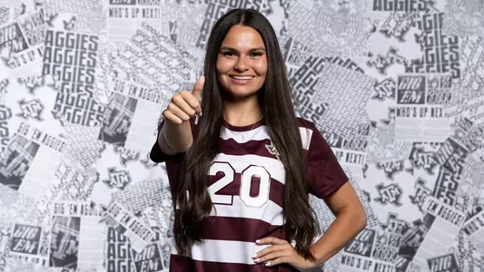 Olivia Fetzer flashes a smile and a Gig 'em at the Aggies' 2024 content day portrait shoot