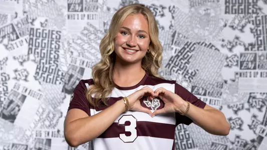 Bella James performs an immaculate hands heart over the Texas A&M logo on her jersey