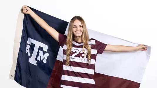 Trinity Buchanan dons an Aggie maroon jersey while unfurling an A&M logo-themed Lone Star flag during her recruiting trip portrait shoot