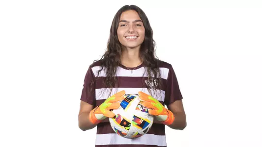 Erica Defferding Recruiting Visit Portrait - wearing goalkeeper mitts while putting a firm two-hand grip on a ball
