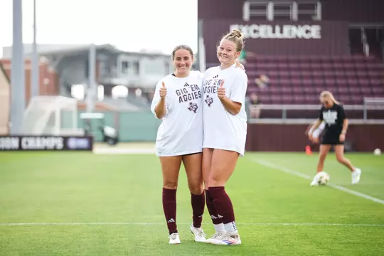Eloise Descheneaux and Bailey Cate enjoy a prematch moment before the Aggies battle Baylor.