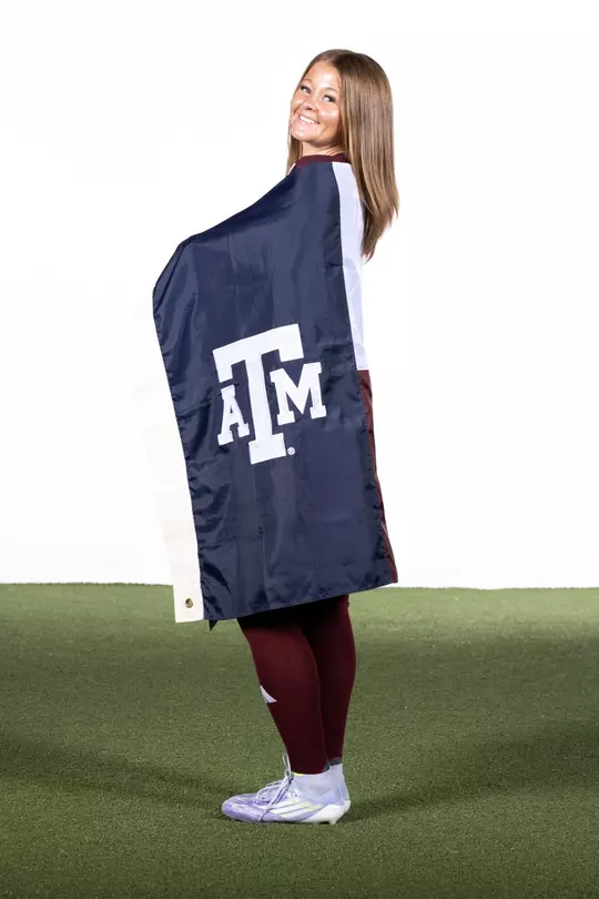 Bailey Cate cloaked in a Texas A&M flag during her 2025 media day portrait shoot.