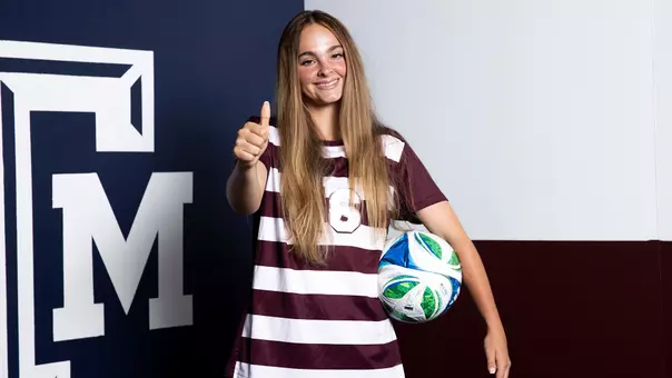 Trinity Buchanan gives a Gig 'em and flashes a smile during her media day portrait shoot