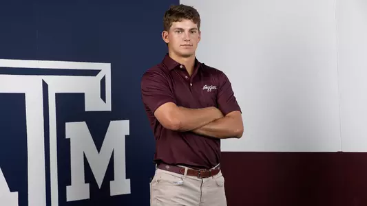 Aaron Pounds poses arms folded in front of a Lone Star Flag themed Texas A&M backdrop