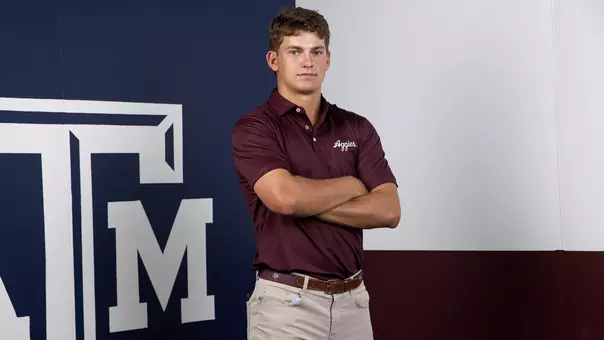 Aaron Pounds poses arms folded in front of a Lone Star Flag themed Texas A&M backdrop