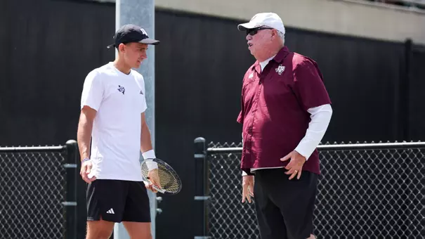 COLLEGE STATION, TX - March 29, 2026 - Theo Papamalamis of the Texas A&M Aggies and Head Coach Steve Denton of the Texas A&M Aggies during the game between the Tennessee Volunteers and the Texas A&M Aggies at Mitchell Tennis Center in College Station, TX. Photo By Micah Richter/Texas A&M Athletics