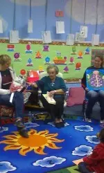 Jordan Barncastle and Haley Schneider assist Betty Doris Laroe in reading to kids at Wheelock Elementary School.