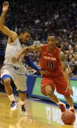 Robert Turner (14) drives to the basket against Kansas Jayhawks guard Frank Mason (0).