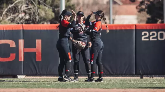 Payton Jackson, Peyton Blythe and Demi Elder high five in the outfield