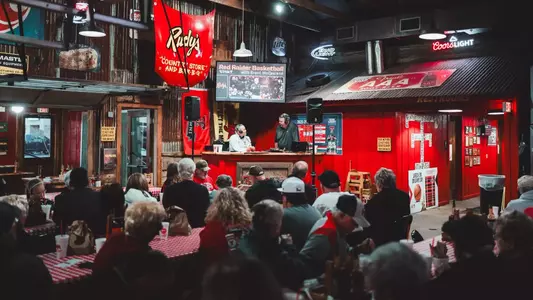 Grant McCasland and Geoff Haxton sit together and talk on stage at Rudy's BBQ during the weekly Texas Tech basketball radio show.