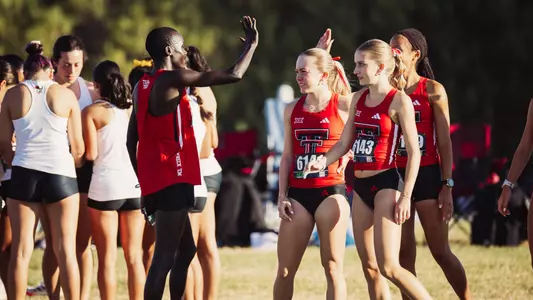 Titus Kimaru high fiving some members of the Texas Tech women's cross country team