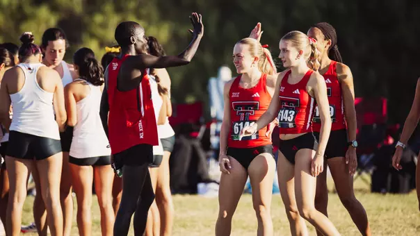 Titus Kimaru high fiving some members of the Texas Tech women's cross country team