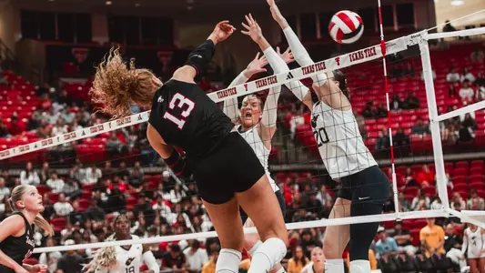 Shelby Ignash hitting a ball between two West Virginia defenders