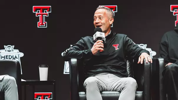 Grant McCasland smiles speaking into a microphone on the main stage at Big 12 Media Day